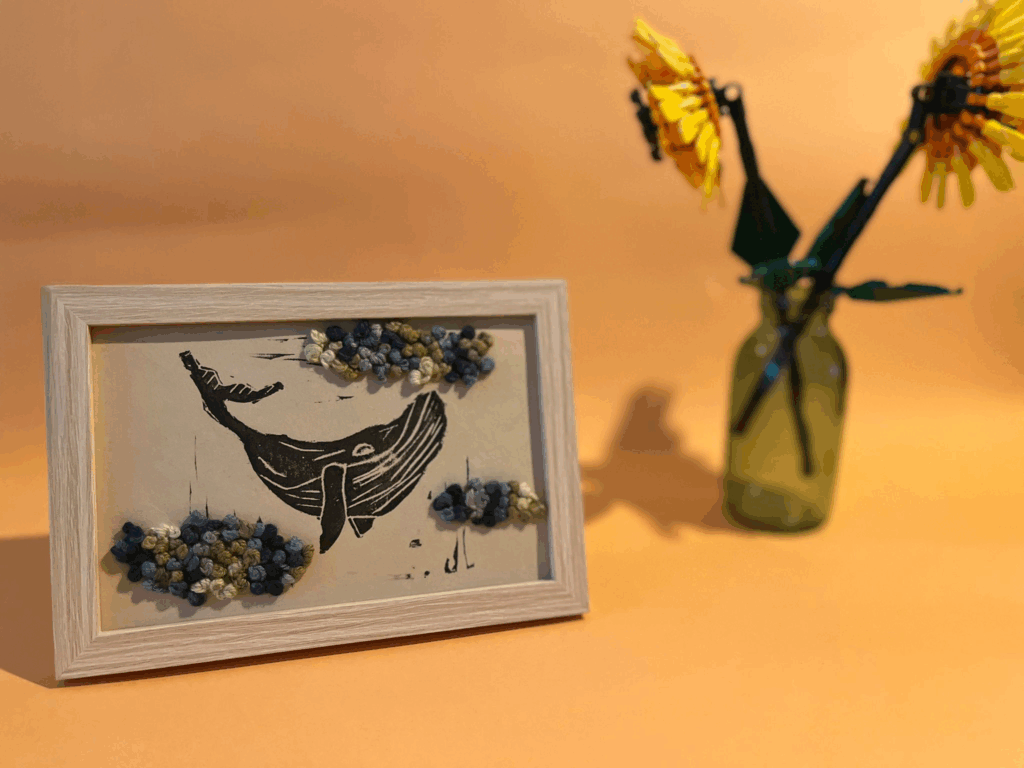 Photographie d'une linogravure-broderie de baleine dans les nuages