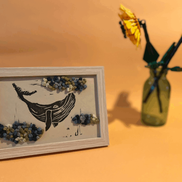 Photographie d'une linogravure-broderie de baleine dans les nuages