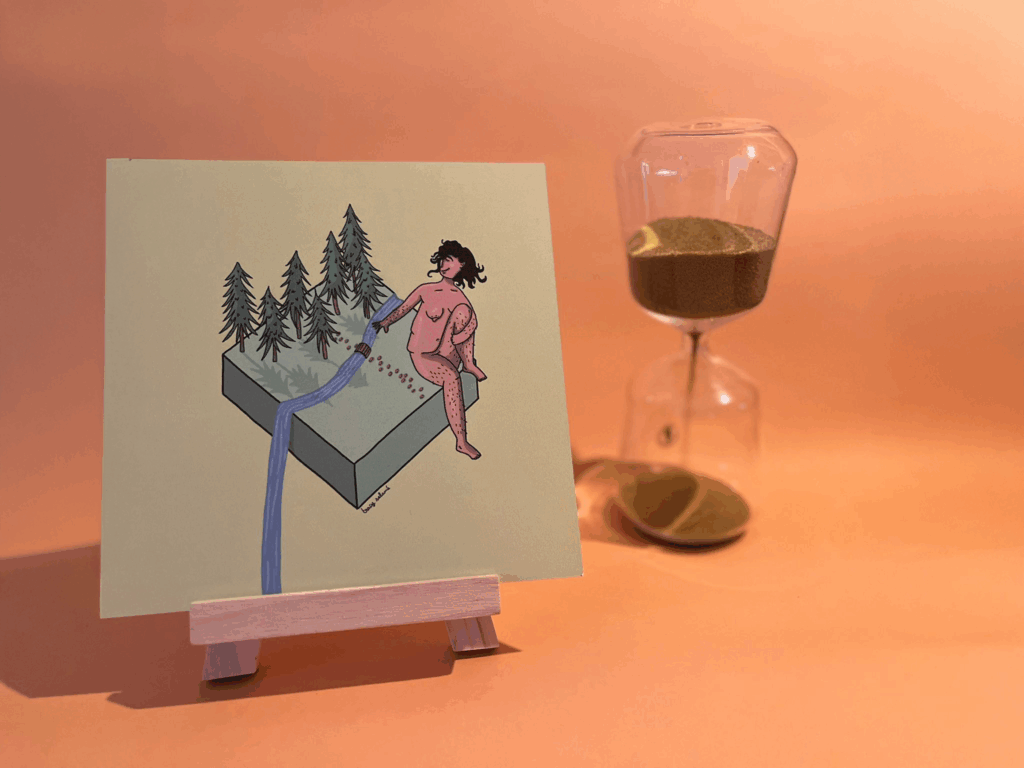 Photographie de l’œuvre en forêt qui représente un personnage assis sur un cube avec une forêt et une rivière qui déborde du cube et tombe hors cadre