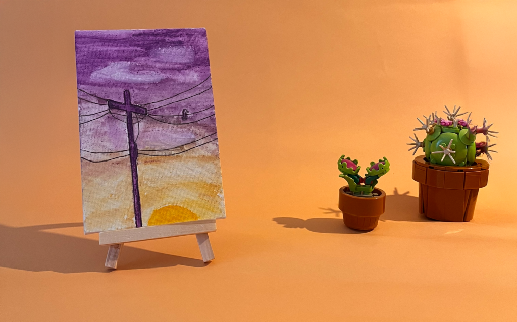 Photographie de l'oeuvre unique originale : un lever de soleil allant du haut violet au bas jaune, devant il y a un poteau électrique et ses fils