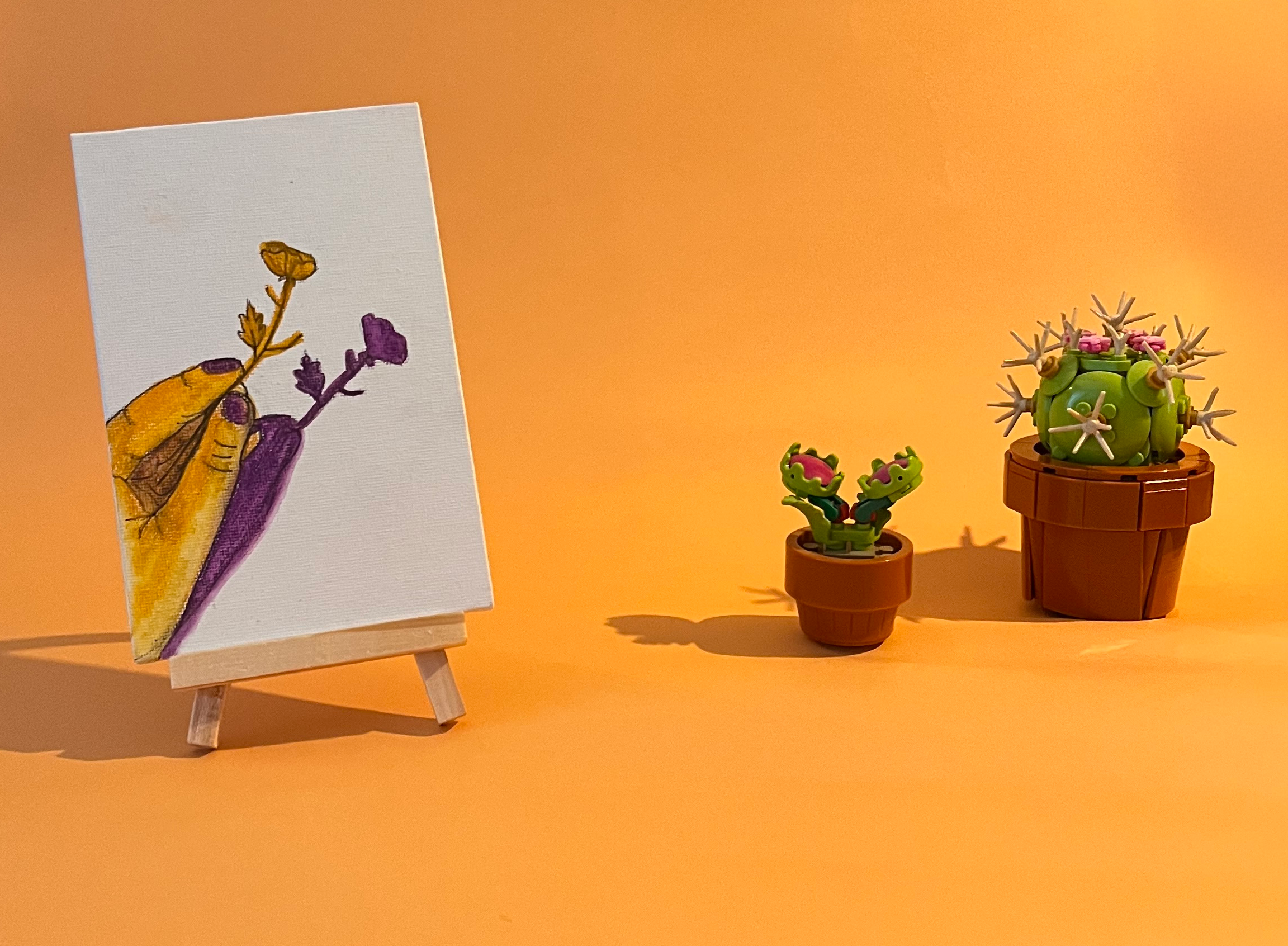 Photographie de l'oeuvre unique originale : une main tenant une fleur, on voit aussi son ombre projetée au sol en violet